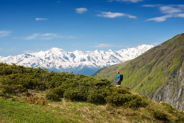 Fototapeta premium Man traveler is standing on a green mountain slope