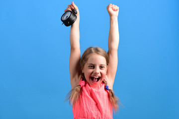 Kid in pink dress with cute braids holds alarm clock