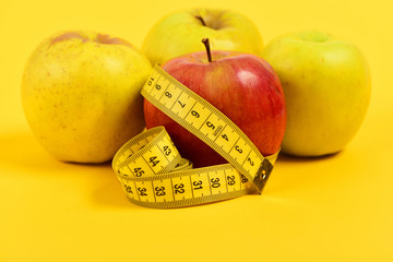 Apples of red and yellow colour wrapped with measuring tape