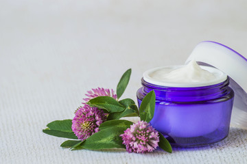 Fototapeta na wymiar Natural cosmetic. A jar with cream for face and body skin care and fresh clover flowers on a light background.