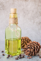  Cedar cones with nuts and a glass bottle with oil on a gray background. The source of natural vitamins and minerals. Used in folk medicine and cooking.