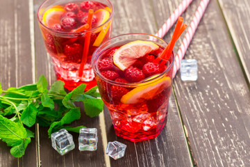 Summer drink with raspberries, lime and ice on a old wooden table