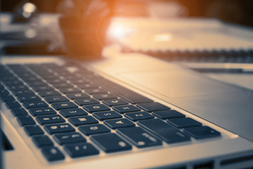 Close up detail view of a laptop computer keyboard with the light shining on the keys with high contrast. Interior.