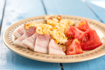 Flat lay fried eggs breakfast with domestic raw bacon and tomato salad