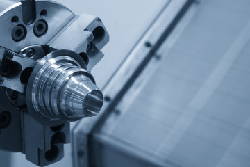 The steel cone part chucked at the CNC lathe or CNC turning machine in the light blue scene.The new machining technology process.