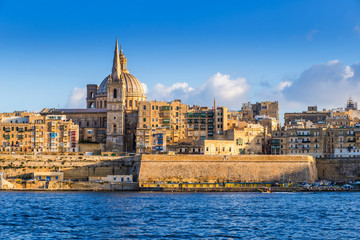 Fototapeta premium Valletta, Malta - The beautiful Saint Paul's Cathedral and the ancient walls of Valletta in the morning with clear blue sky