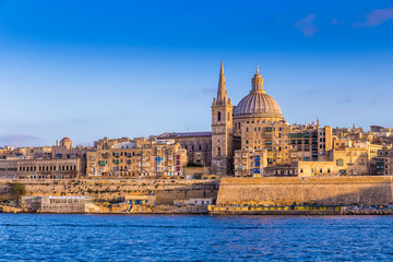 Fototapeta na wymiar Valletta, Malta - The beautiful Saint Paul's Cathedral and the ancient walls of Valletta in the morning with clear blue sky