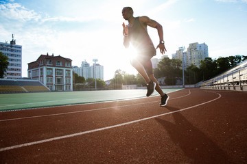 Male runner practicing his sprint in athletics stadium racetrack