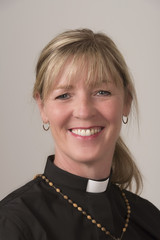 Portrai of a woman priest with blond hair and a big smile