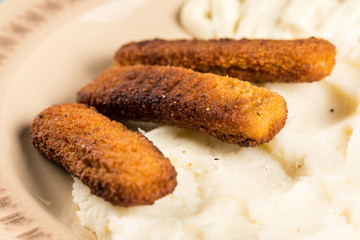 Flat lay mashed potatoes served with fish meat sticks on the plate