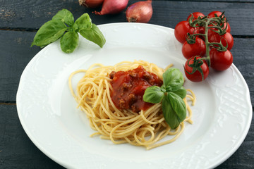 Plate of delicious spaghetti Bolognaise or Bolognese with savory minced beef and tomato sauce garnished with parmesan cheese and basil
