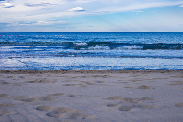Beautiful dreamy sand beach with blue sky and sea with waves in the background during summer