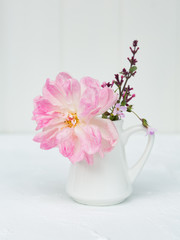 Pink English rose in a jug with pink lilac and delicate wild flowers