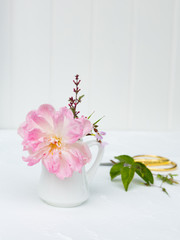 Pink English rose in a jug with pink lilac, delicate wild flowers, scissors and cuttings