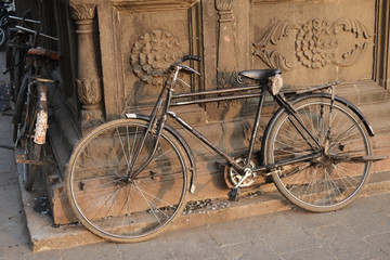 Naklejka na ściany i meble Old indian bicycle leaning on the temple wall.