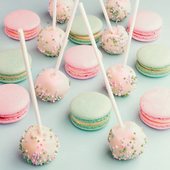 Close-up of colorful macaroons mixed with cake pops with icing on sticks