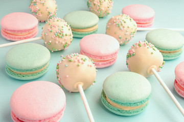 Close-up of colorful sweet macaroons mixed with cake crumbs with icing on sticks on blue background