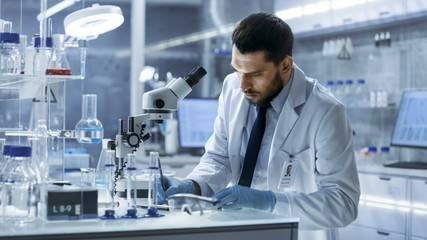 Research Scientist Writes Down Observations. He's Conducts Experiments in Modern Laboratory.