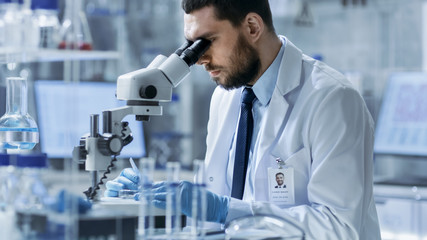 Research Scientist Adjusts Specimen in a Petri Dish and Looks on it Into Microscope. He's Working...