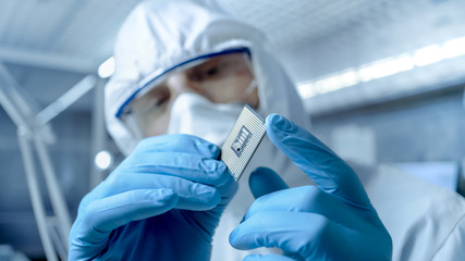 In a Secure High Level Laboratory Scientists in a Coverall Conducting a Research. Chemist Adjusts Samples in a  Petri Dish with Pincers. © Gorodenkoff