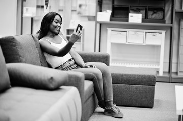 Obraz premium Portrait of a beautiful african american woman taking a selfie in the shop. Black and white photo.
