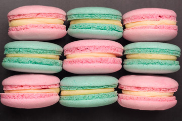 Pink and green colorful macaroons on black background. Flat lay. Top view