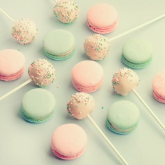 Sweet colorful macaroons mixed with cake pops served lollipop style on sticks. Flat lay