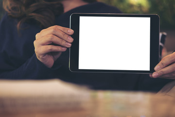 Mockup image of a woman holding and showing black tablet with blank white screen in cafe