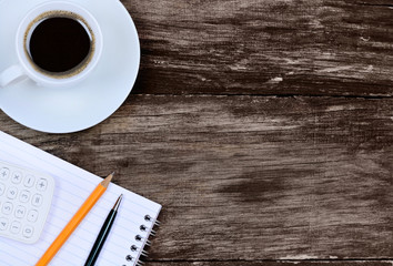 Notepad with calculator pencil and coffee cup on table