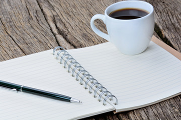 Notepad with pen and coffee cup on desk