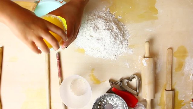Bambina impasta con farina e uova su tavolo di legno per gioco