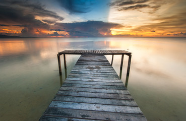 Fototapeta na wymiar View of beautiful sunset with wooden jetty. image contain soft focus due to long expose.