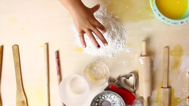 Bambina impasta con farina e uova su tavolo di legno per gioco
