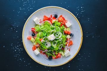 Greek salad of fresh vegetables and cheese. On a wooden background. Top view. Free space for your text.
