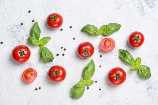 Fresh cherry tomatoes with basil leaves and black pepper on a stone table, vegetable pattern, top view