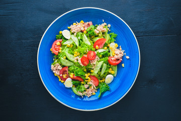 Salad with fresh vegetables and tuna. On a wooden background. Top view. Free space for your text.