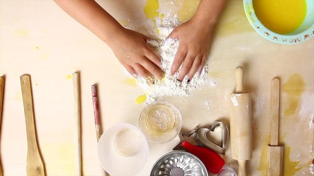 Bambina impasta con farina e uova su tavolo di legno per gioco