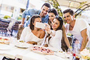 Group of young beautiful people sitting in a restaurant and taki