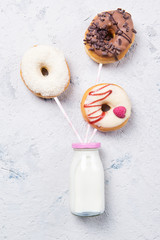 Fototapeta na wymiar Donuts on a drinking straws with bottle of milk on a stone table, top view