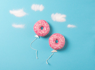 Pink donuts on blue background, creative food minimalism, donut in a shape of balloon in the sky...