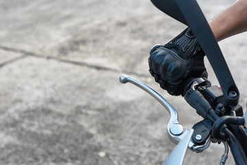Close up A man hand wearing a motorcycle glove is driving a motorbike to avoid traffic congestion in the city.