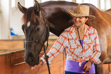 Cowgirl standing next to brown horse friend