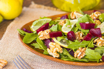 Salad with arugula, beets and nuts In a glass jar in a wooden plate