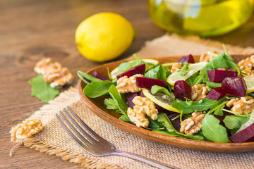 Salad with arugula, beets and nuts In a glass jar in a wooden plate