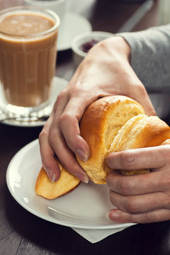 Woman's Hands Tearing Open A Croissant For Breakfast In Cafe