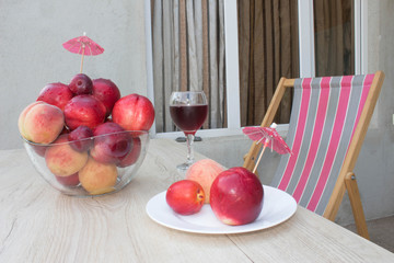 fruit on the table. Peaches, nectarine, plums. A glass of red  wine