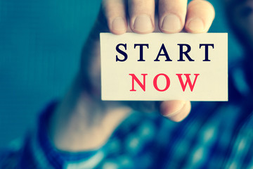 START NOW, message on white card man showing, may used for different words and background. Aged toned.