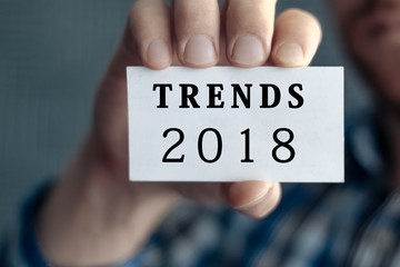 TRENDS 2018, message on white card man showing, may used for different words and background. Aged toned.