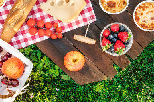 Picnic food on wooden board and green grass with copyspace