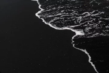Abwaschbare Fototapete Schwarz weißer ozeanschaum auf schwarzer sandvulkanstruktur